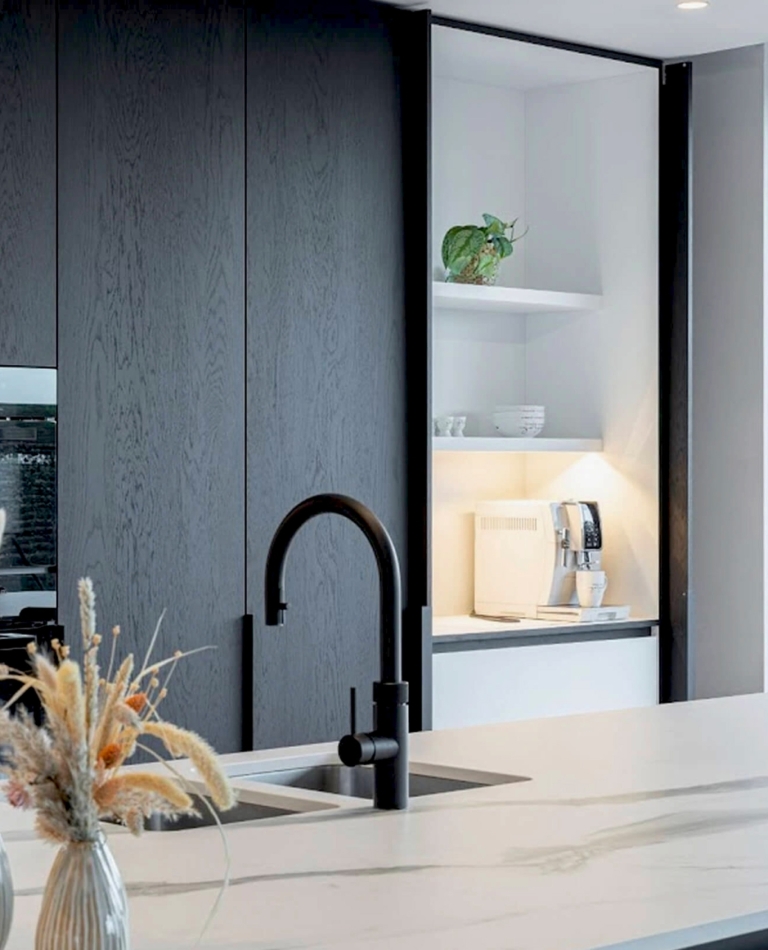 Moderne keuken op maat met koffienis in Zarren regio Diksmuide, West-Vlaanderen met donker hout, marmeren werkblad en zwart kraanwerk.