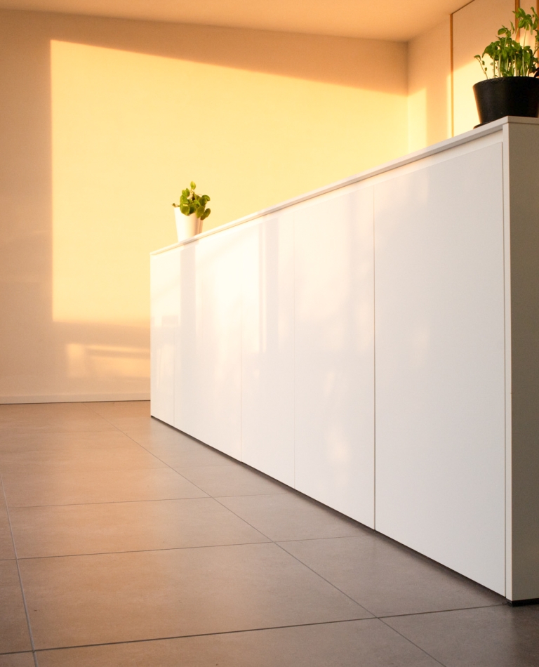 Wit kookeiland op maat met minimalistische fronten en ruime werkzone in moderne keuken.
