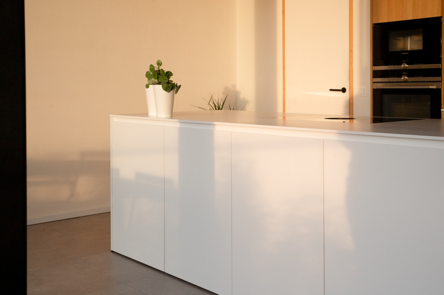 Wit kookeiland op maat met minimalistische fronten en ruime werkzone in moderne keuken.