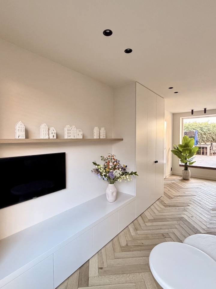Moderne leefruimte met maatwerk tv-meubel, kastenwand en visgraatparket in Roeselare, West-Vlaanderen