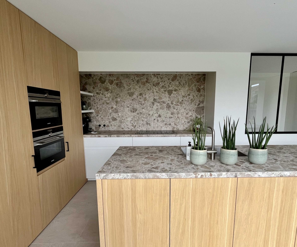 Moderne maatwerk keuken met ingebouwde toestellen, natuursteen werkblad, open schappen en een doordachte indeling binnen de door de architecte aanbevolen uitbouw.