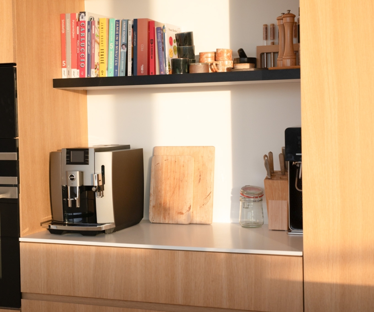 Open schappen in keuken op maat met houten fronten, kookboeken en subtiele decoratie.