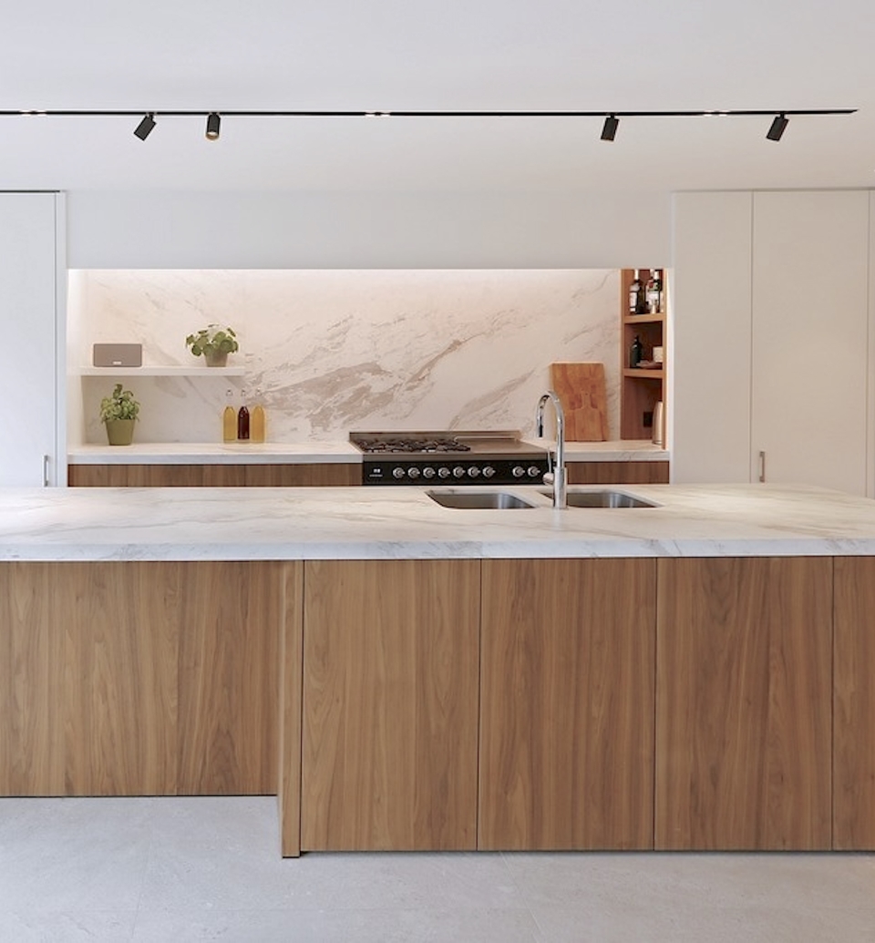 Moderne maatwerkkeuken met warm hout, marmeren werkblad en strak keukeneiland, ontworpen met hoogwaardige materialen en minimalistische afwerking.